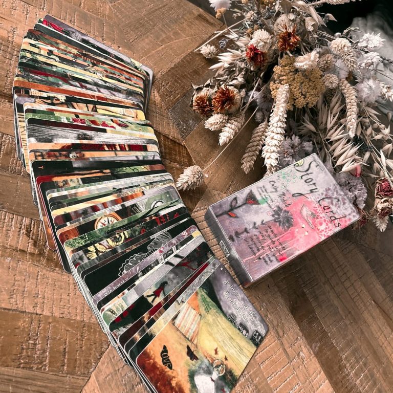 Een verzameling kunstkaarten en een klein boekje liggen op een houten tafel.