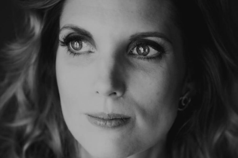 Portret van Inge met golvend haar en een serene blik. Zwart-wit afbeelding. Ze laat haar kwetsbaarheid zien bij een afwijzing.