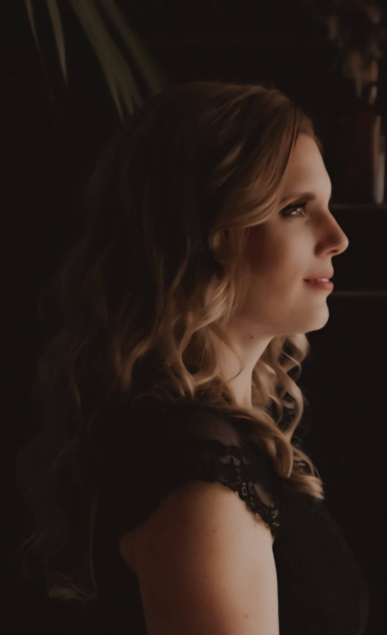 Vrouw met lange, golvende haren die naar rechts kijkt, met een sierlijke achtergrond. Persoonlijke begeleiding