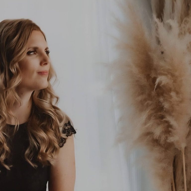 Inge in een zwart shirt, staand naast een decoratieve plant. De ervaringen van mijn klanten maken mij een gelukkig mens